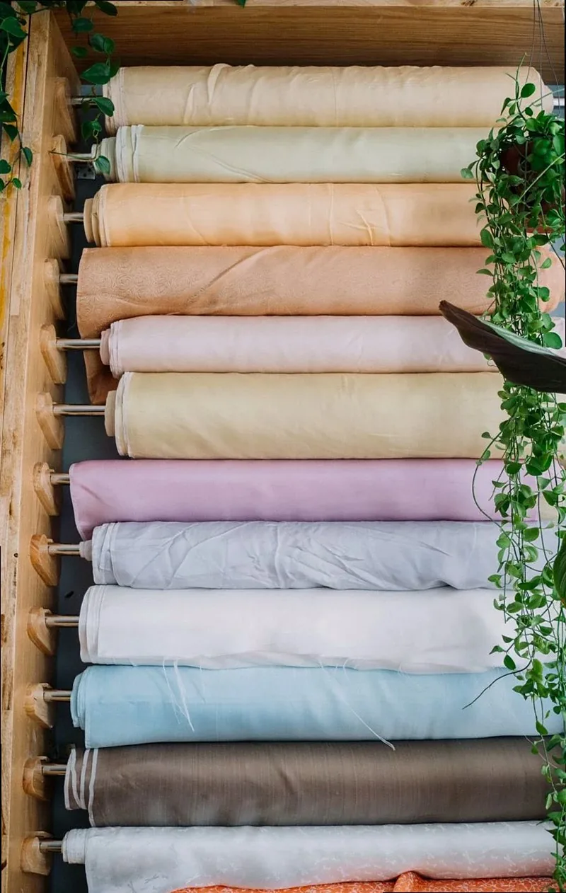 Vertical shot of vibrant fabric rolls in a tailor shop with greenery.
