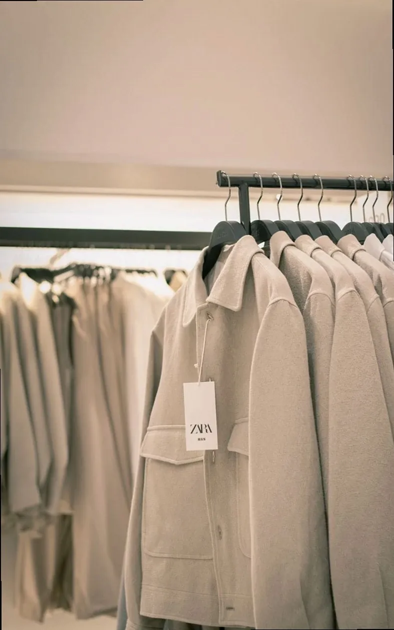 Stylish beige coats neatly arranged on racks in a modern clothing store interior.